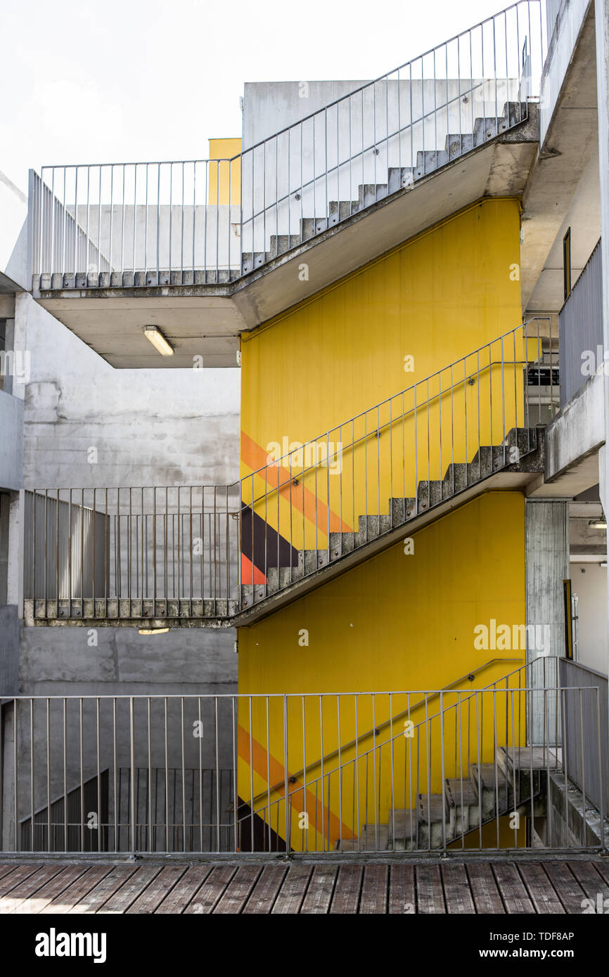 La scala a tre piani. Giallo parete di calcestruzzo. Scala intorno alla struttura di calcestruzzo. Foto Stock