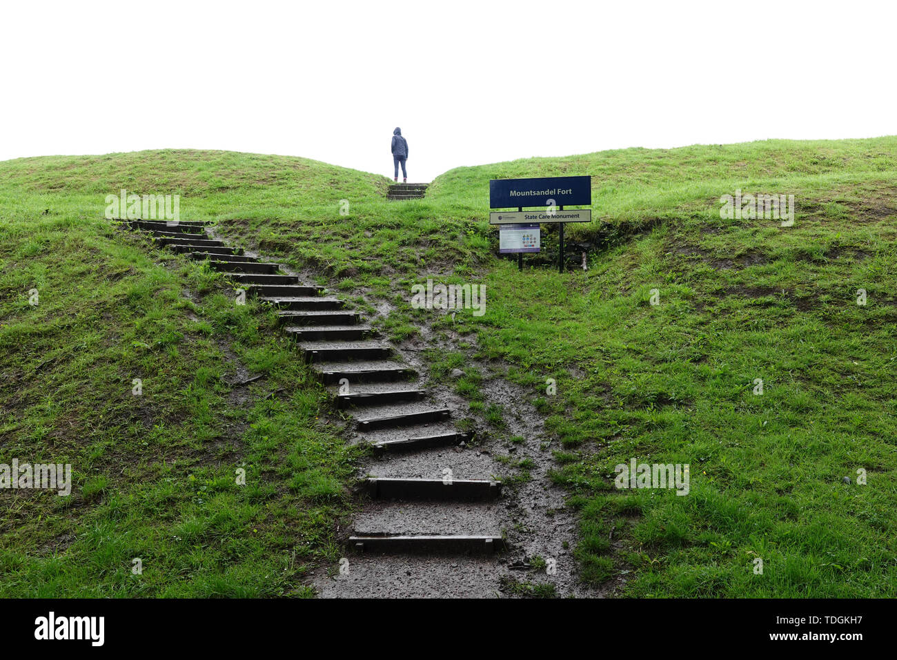 Una persona che sta in cima alla scalinata che conduce al Monte Sandel Fort rovine di argilla in un giorno di pioggia. Lo scopo esatto del terrapieno rimane sconosciuto. Foto Stock