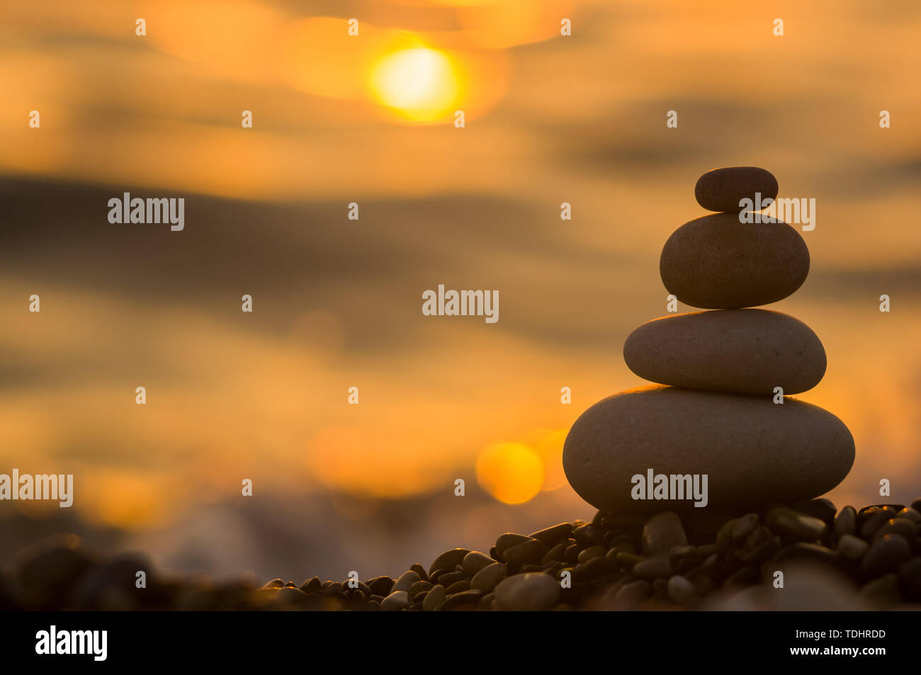 Piramide piegata Zen pietre ghiaia sul mare spiaggia al tramonto Foto Stock