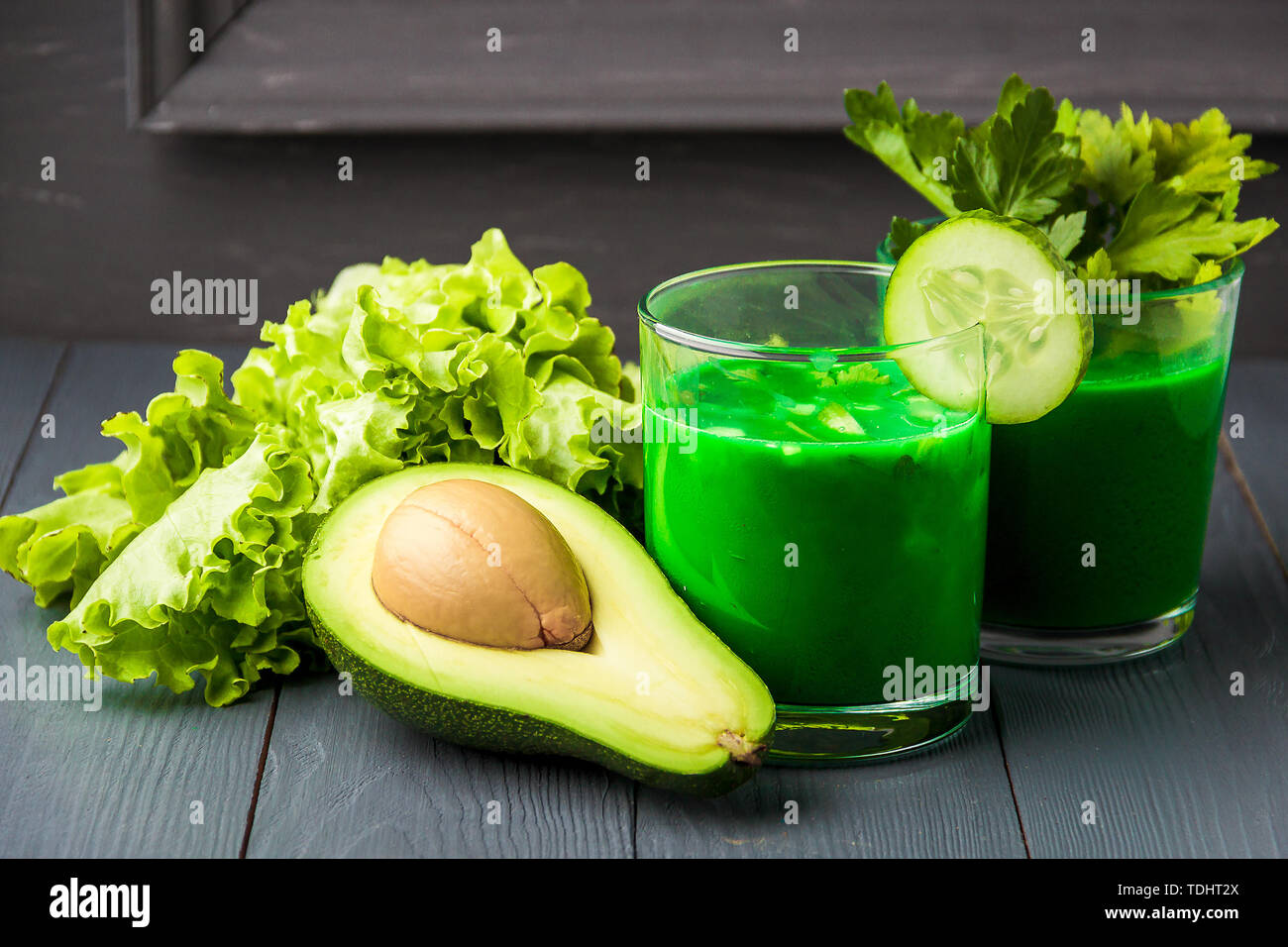 Bicchiere di freschi succhi di verdura in grigio sullo sfondo di legno. Foto Stock