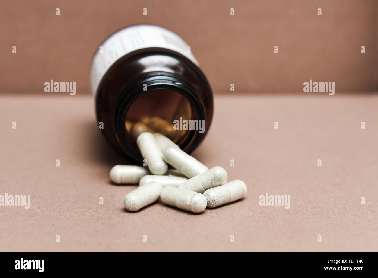 Vitamine in una bottiglia. Health supplement compresse con la guarigione naturale proprietà. Ravvicinata di una capsula di vitamina fuoriuscita dalla bottiglia Foto Stock