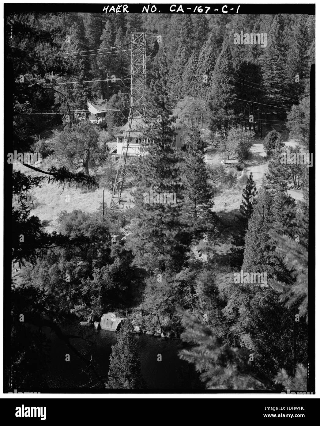 Panoramica di estrema east end di Big Creek città attraverso POWERHOUSE NO. 2 FOREBAY (potente no. 1 AFTERBAY). Torre portando le linee di trasmissione dal potente n. 1 si trova al centro di foto. Dietro la torre è la costruzione di 103. Per foto a sinistra dell'Edificio 103 è in fase di costruzione 105. Vista verso nord. - Big Creek sistema idroelettrico, Big Creek Town, operatore House, Orchard Avenue a Sud di Huntington Lake Road, Big Creek, Fresno County, CA Foto Stock