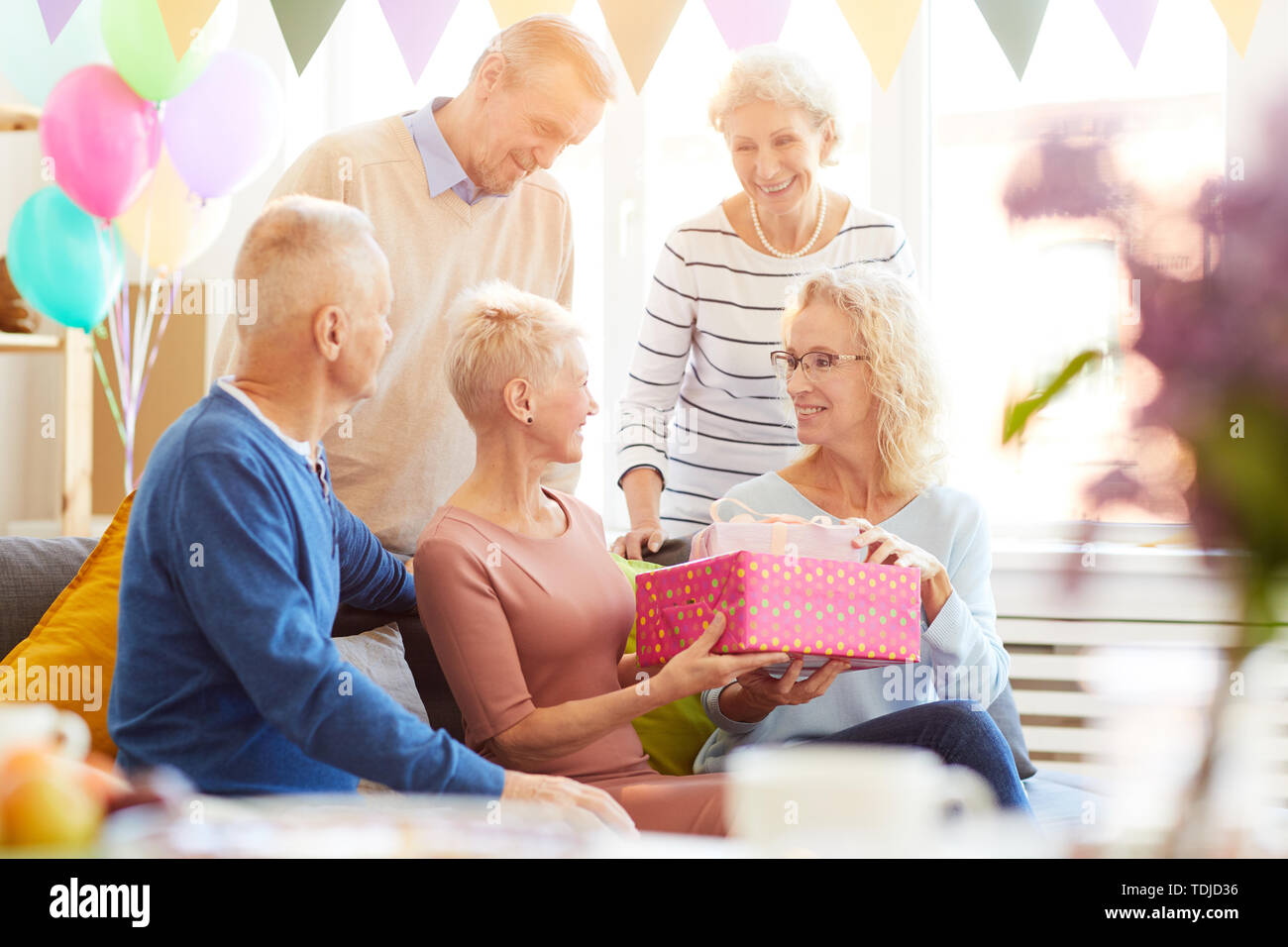 Sorridere persone mature regali di compleanno donna e congratulandomi con lei con una festa di compleanno a casa party Foto Stock