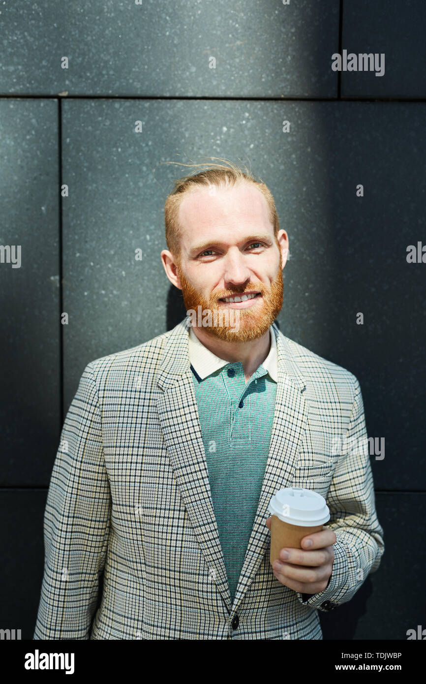 Ritratto di sorridere red-barbuto imprenditore in elegante giacca a scacchi di bere il caffè da asporto cup Foto Stock
