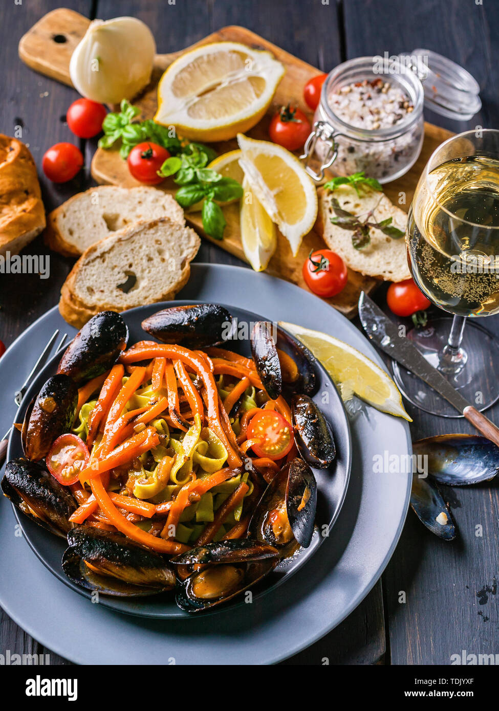 La pasta italiana con le cozze e le verdure. Una tradizionale cucina mediterranea. Scuro dello sfondo in legno Foto Stock