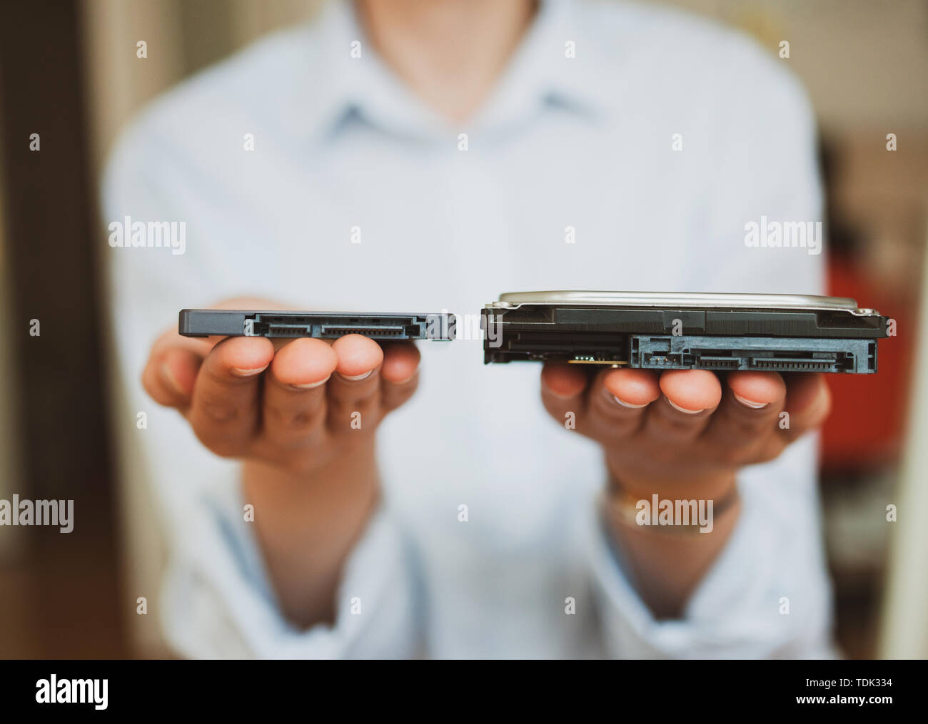Essa donna azienda presentando due diverse generazioni di computer Disks HDD disco rigido e il disco a stato solido SSD - offrendo loro al visualizzatore Foto Stock