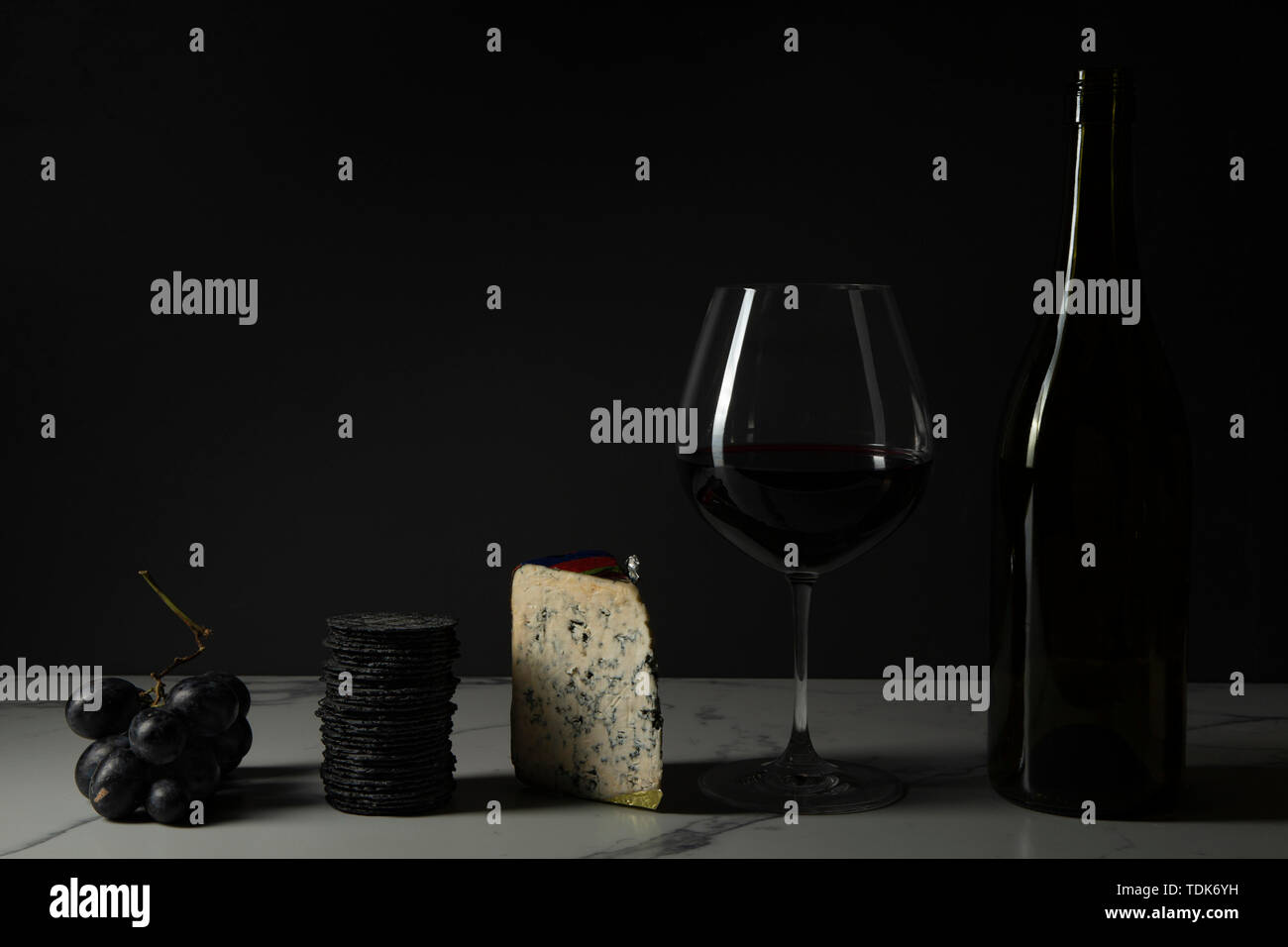 Vino e formaggio, con cracker e Uva su un marmo la superficie della piastrella. Foto Stock