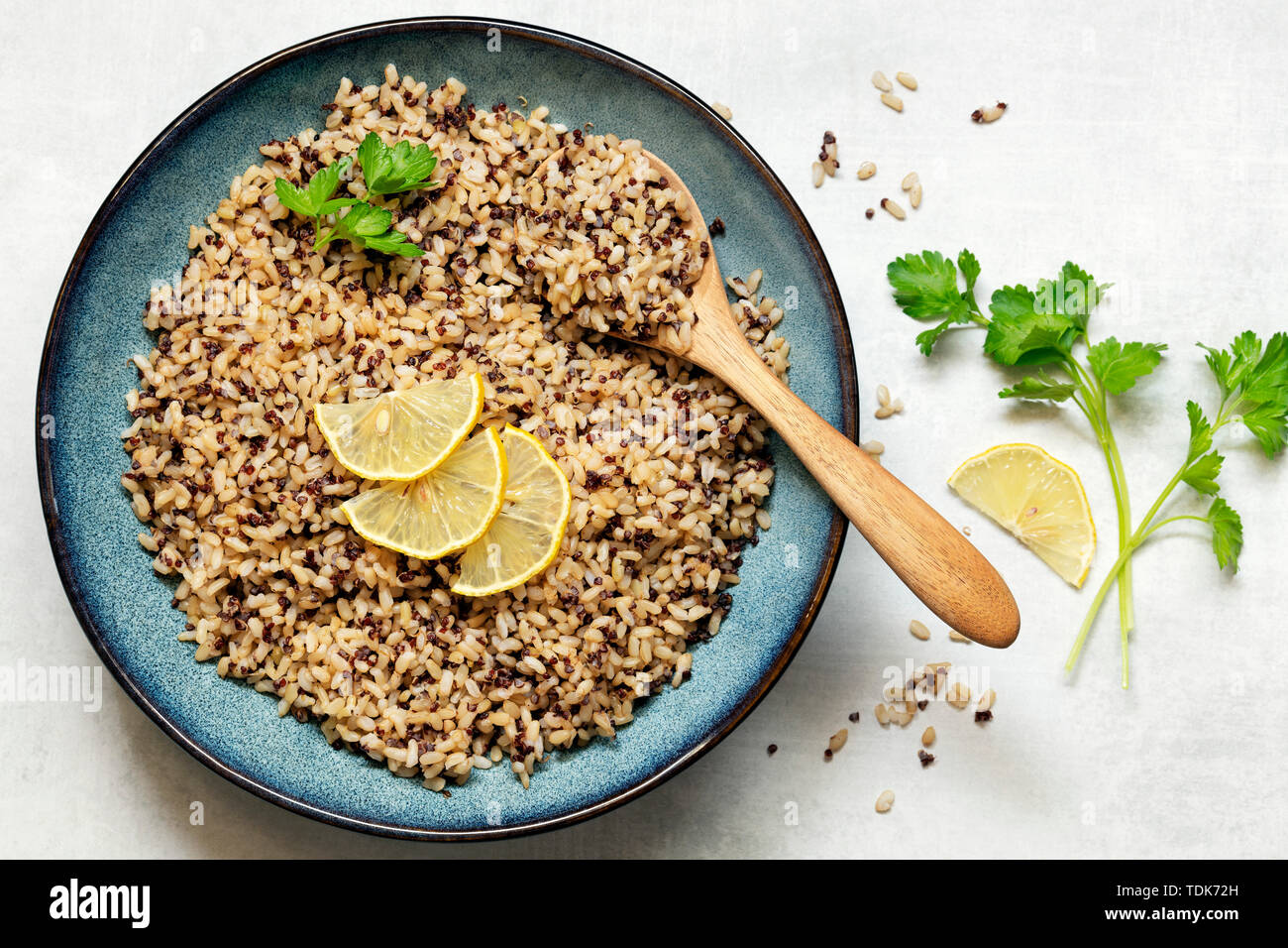 Riso marrone e la quinoa in una ciotola guarnite con fettine di limone e prezzemolo. Foto Stock
