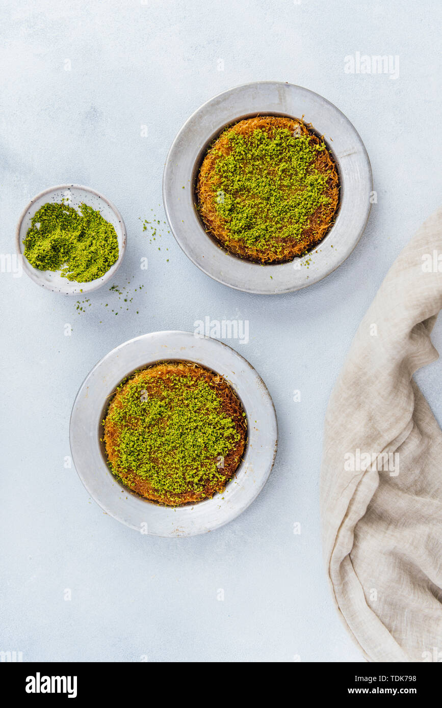Kunefe turco in due teglie accompagnato da una piccola ciotola di pistacchio e sciroppo Foto Stock