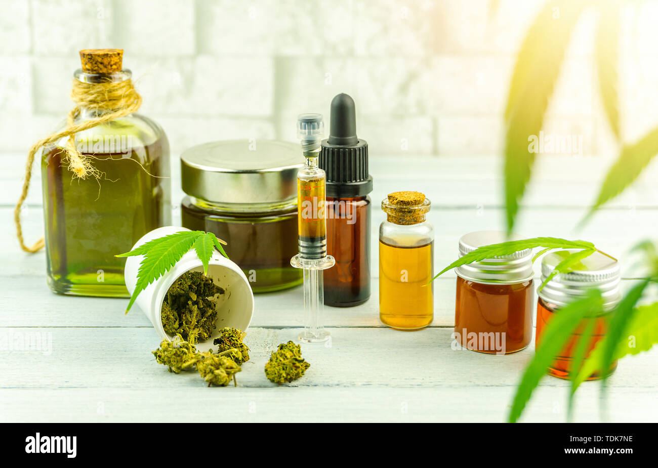 CBD cannabidiolo olio bottiglie di vetro, pillole boccioli di fiori e foglie di cannabis in bright tavolo in legno Foto Stock