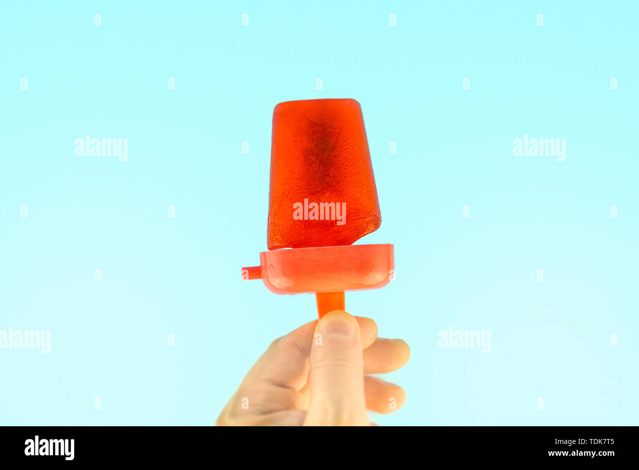 Mano azienda red congelati ghiaccioli Ice Pop contro estate cielo blu sullo sfondo Foto Stock