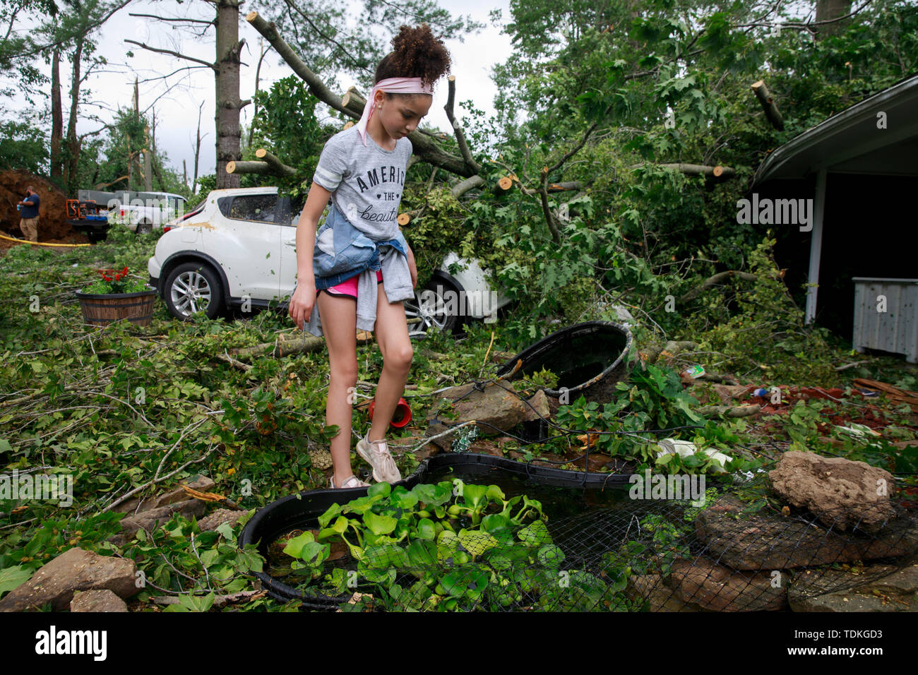 Ellettsville, Indiana, Stati Uniti d'America. 16 Giugno, 2019. Khaliya Francke-Council salvages il suo pesce koi pond dove pesce 7 risultano dispersi, durante l'indomani. Un tornado ha colpito la zona lasciando una patch di danni da Greene County a nord della Contea di Monroe distruggendo alberi, casa, auto e lasciando un percorso di detriti e vivere le linee di potenza sul terreno nella sua scia. Credito: SOPA Immagini limitata/Alamy Live News Foto Stock