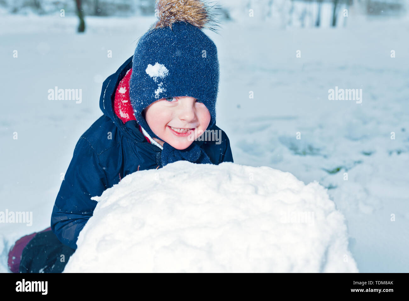 Inverno ritratto di un felice little boy. kid ride e sorrisi. bambino fa un pupazzo di neve. emozione la felicità in vacanza Foto Stock