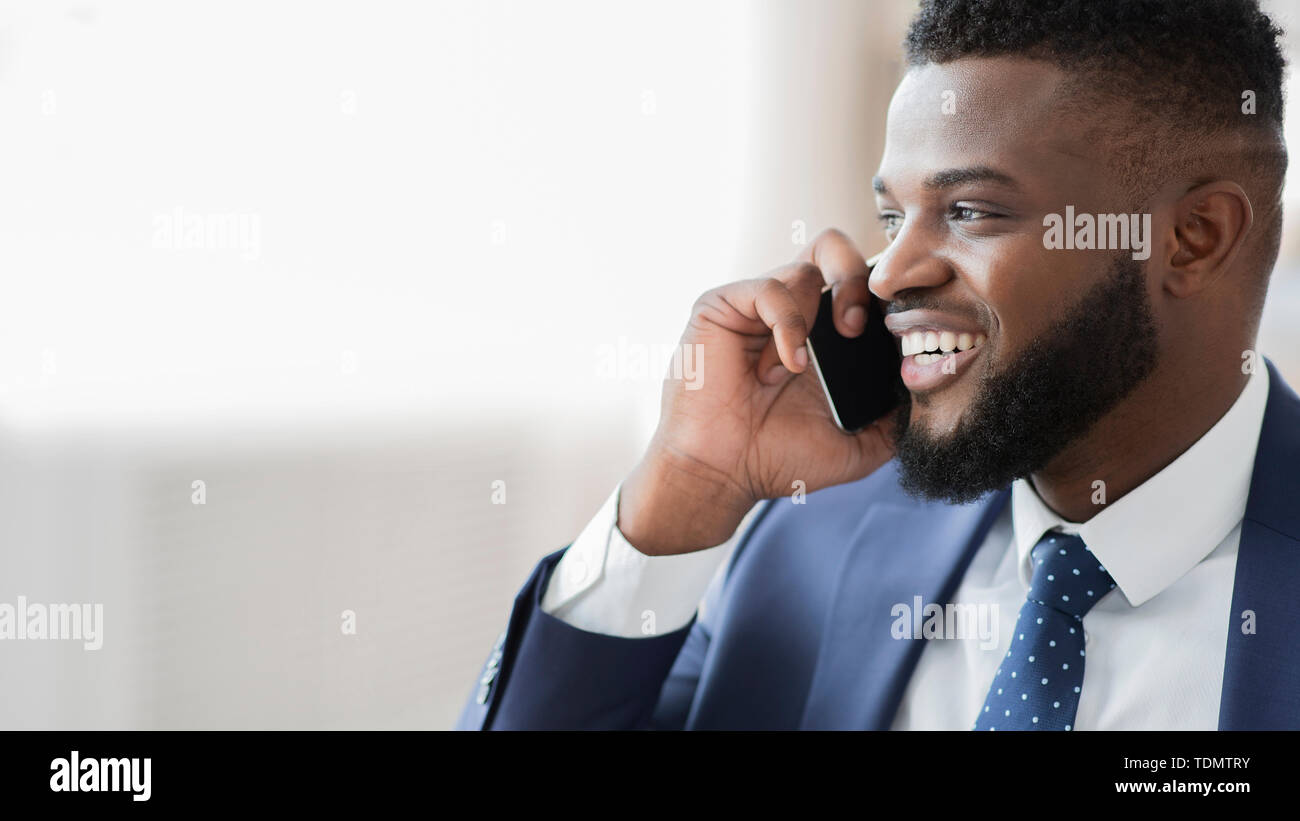 Felice imprenditore africano parlando al cellulare, cercando et spazio vuoto Foto Stock