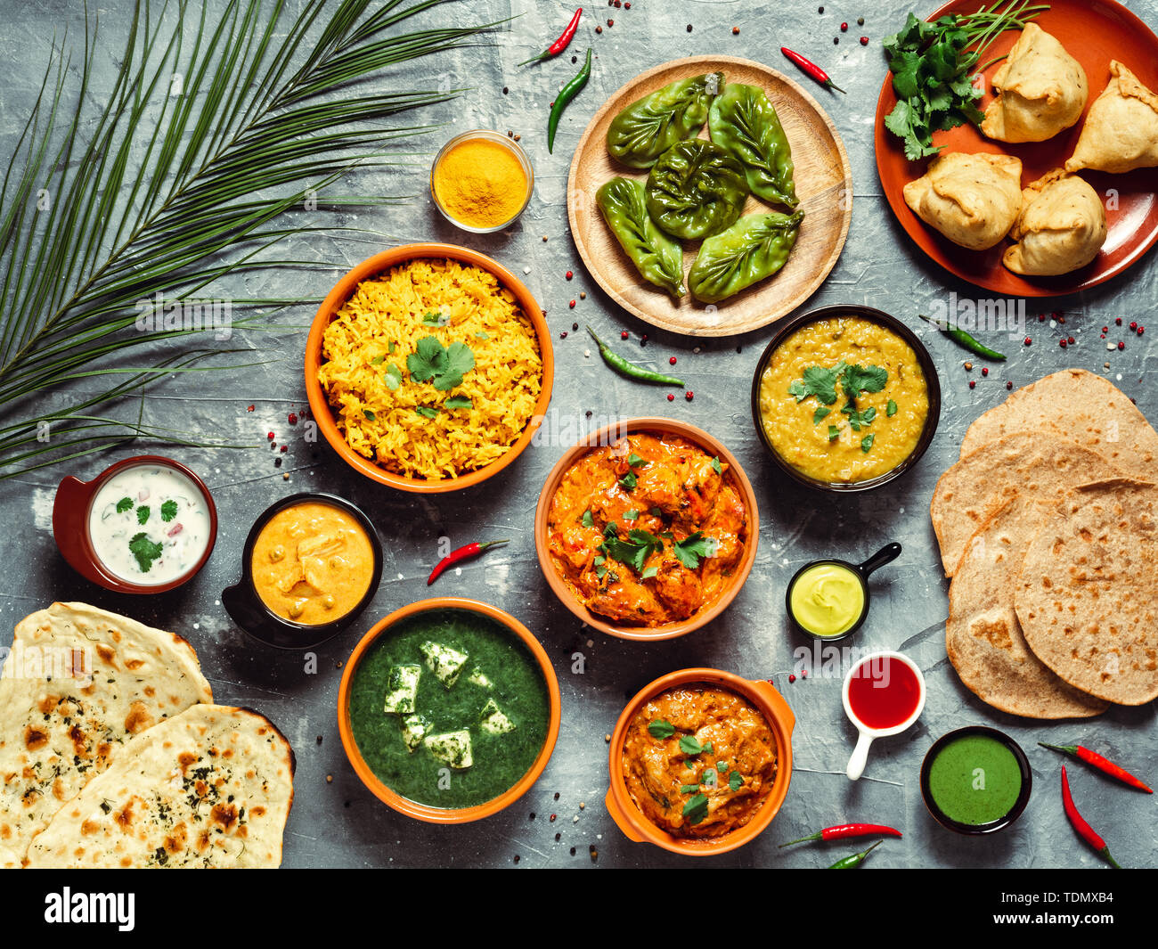 La cucina indiana piatti: tikka Masala, Dal, paneer, samosa, chapati, chutney, spezie. Il cibo indiano su sfondo grigio. Assortimento pasto indiano vista superiore piatta o laici. Foto Stock