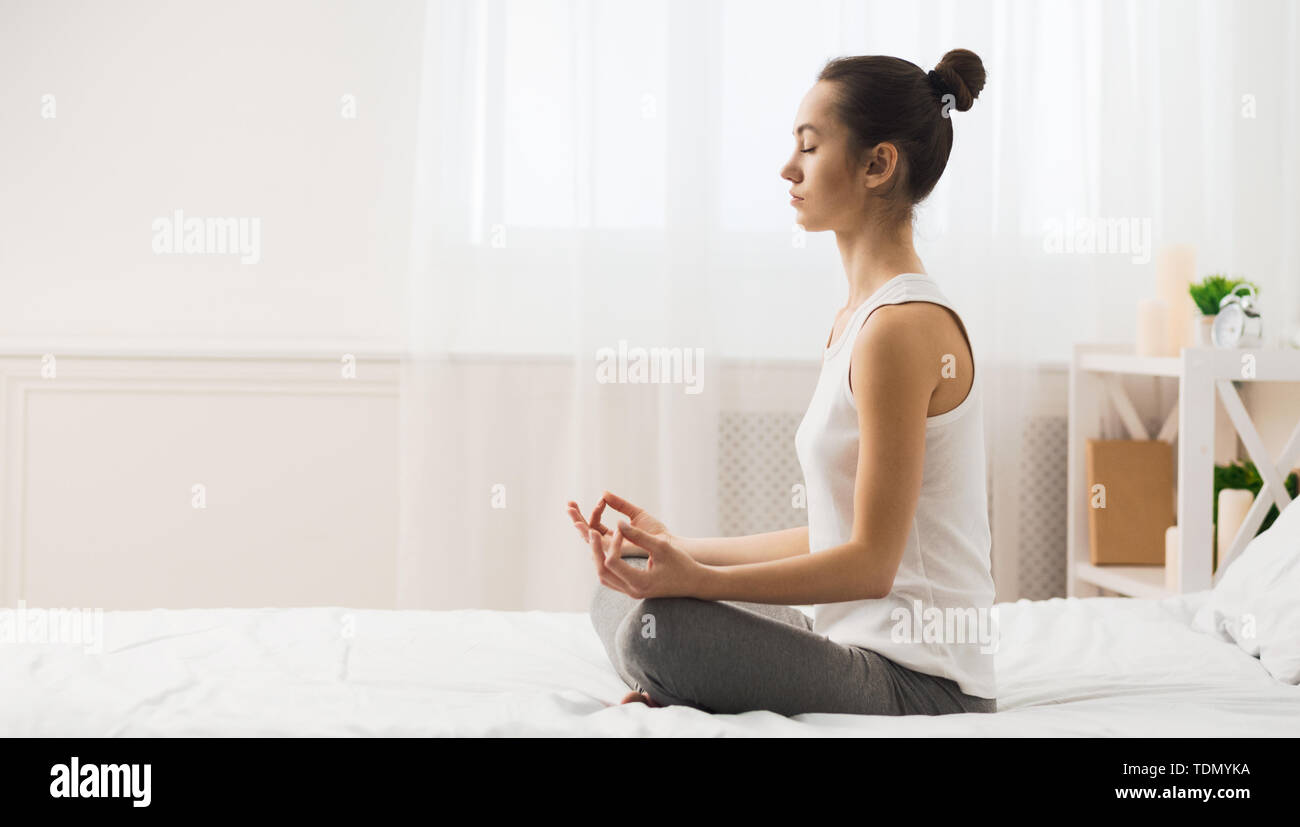 Meditazione del mattino. La donna a praticare Yoga sul letto Foto Stock