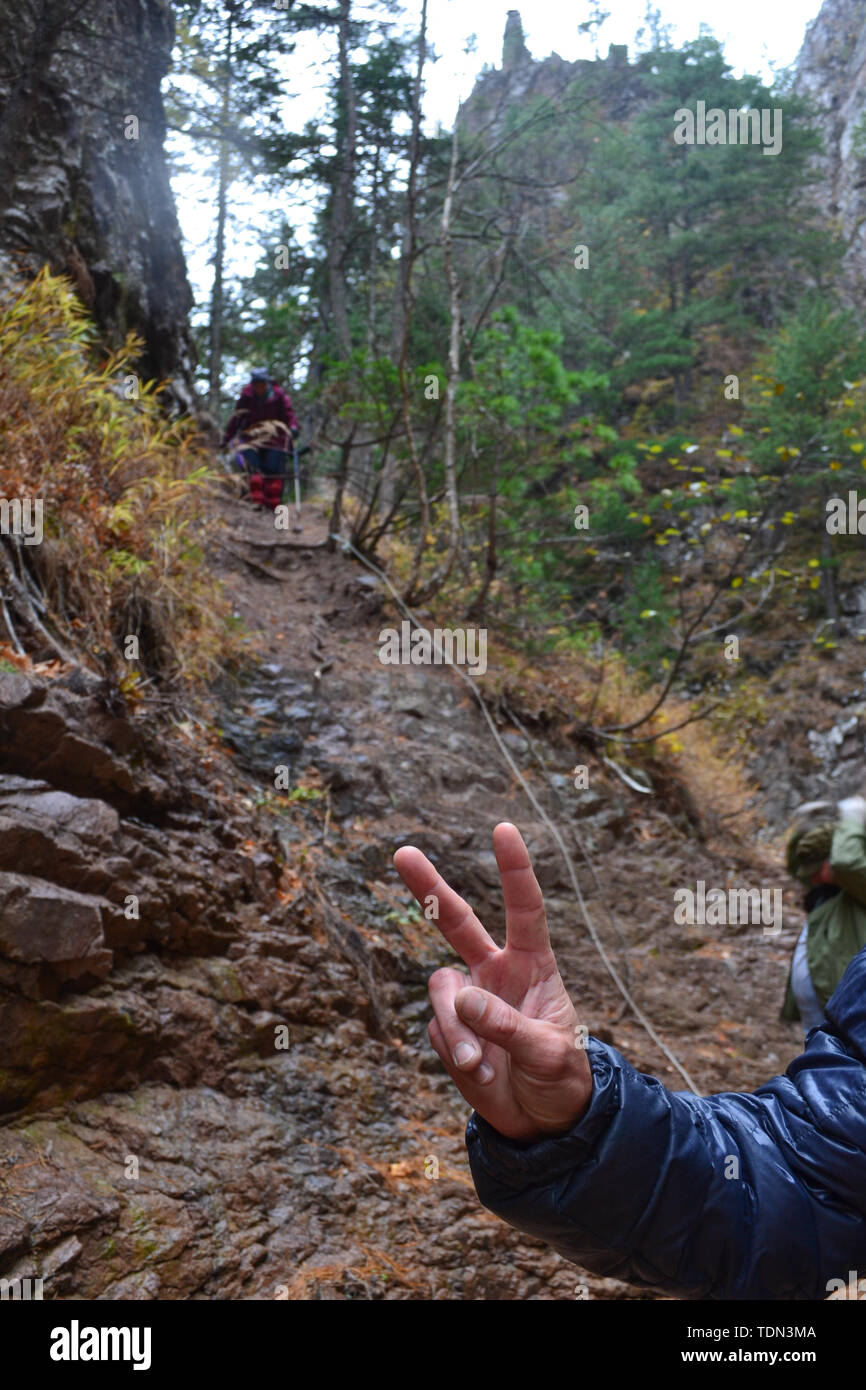 L'uomo mostra segno di vittoria nella foresta Foto Stock