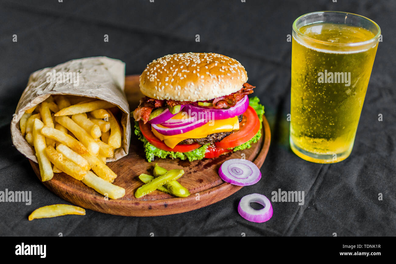 Hamburger e patatine fritte su un tavolo di legno su sfondo nero Foto Stock