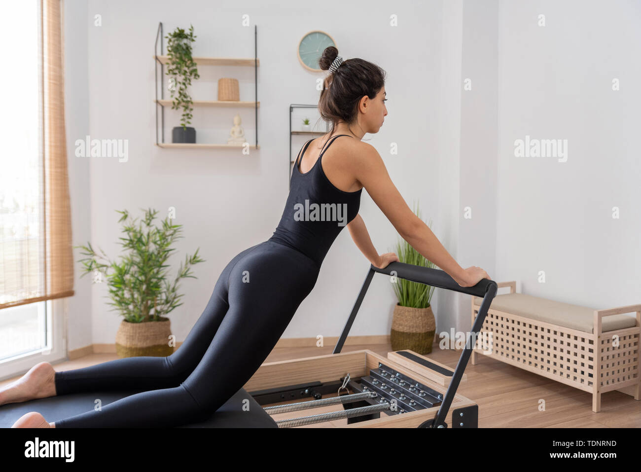 Giovane donna esercita sul pilates reformer bed Foto Stock