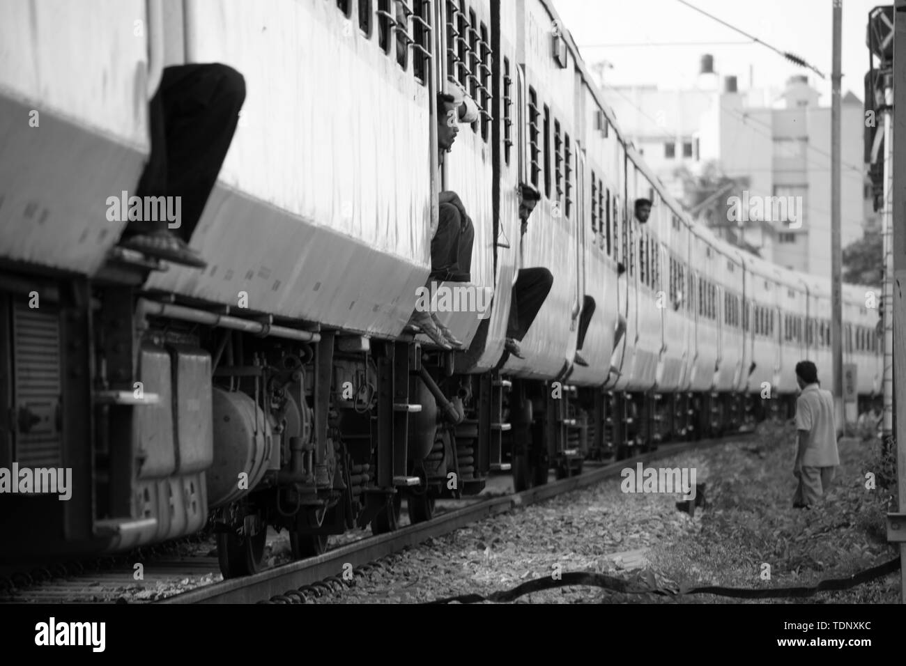 BANGALORE INDIA Giugno 1, 2019 :immagine monocromatica di gente seduta sul bordo della scala fasi di movimento del treno in corrispondenza di Bengaluru dovuta alla non disponibilità di mare Foto Stock