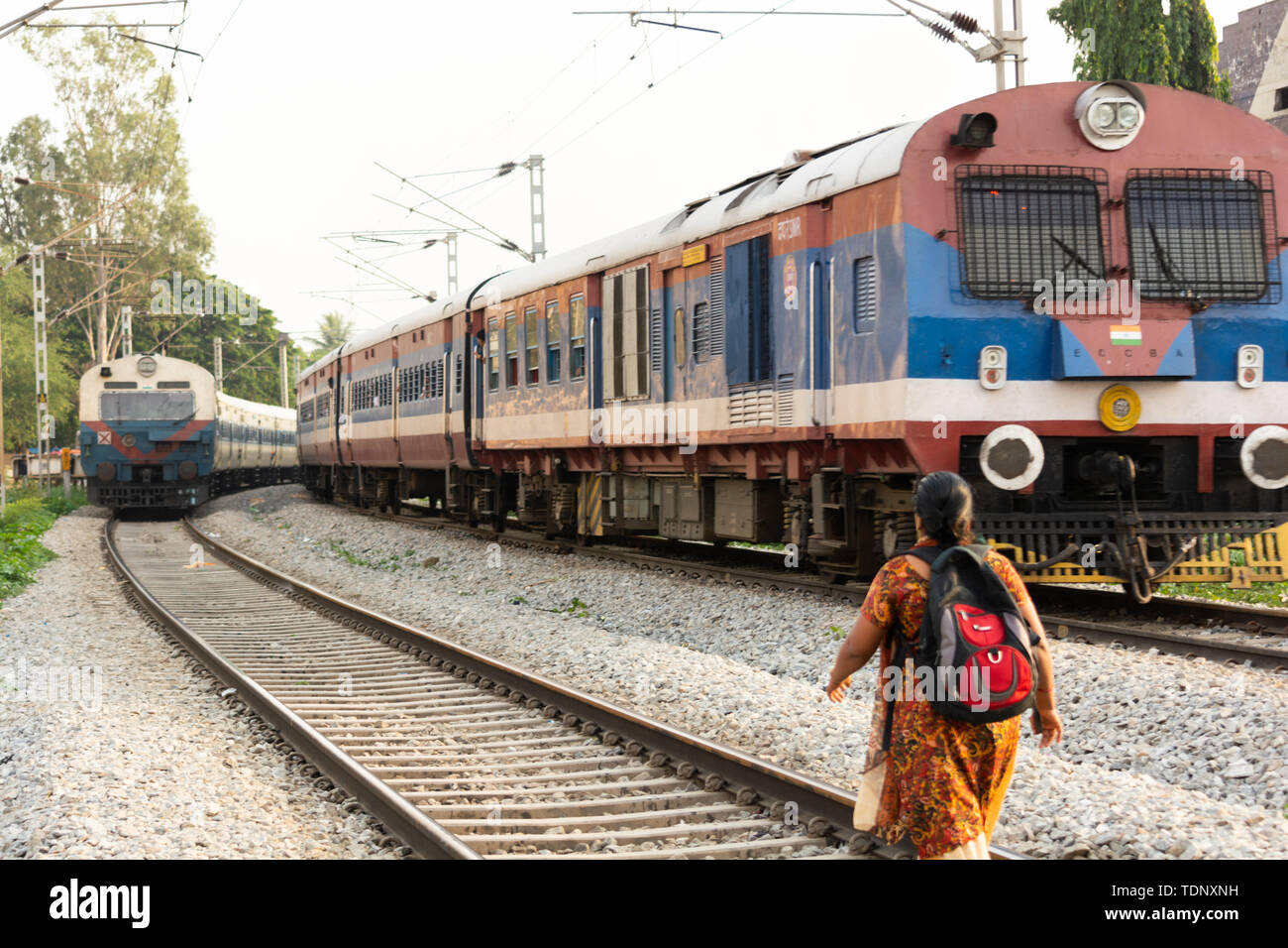 BANGALORE INDIA Giugno 1, 2019 : Donna lavoratore urbano con zaino è camminare sul binario ferroviario linea infront del treno in India Foto Stock