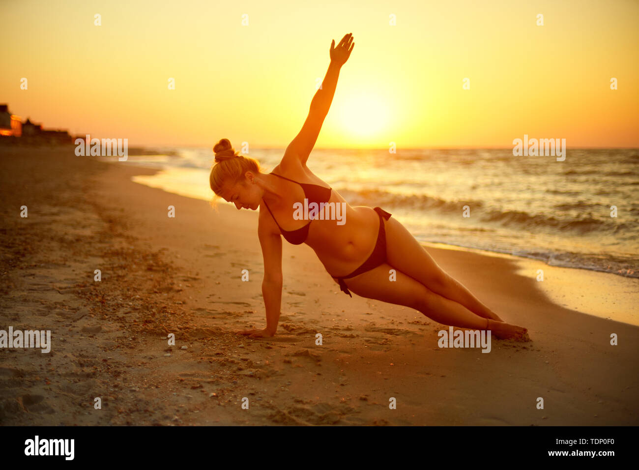 Autentica donna in costume da bagno fare yoga vasisthasana sulla spiaggia di mattina. Reale forma unretouched ragazza silhouette in posizione del cobra asana vicino al mare Foto Stock
