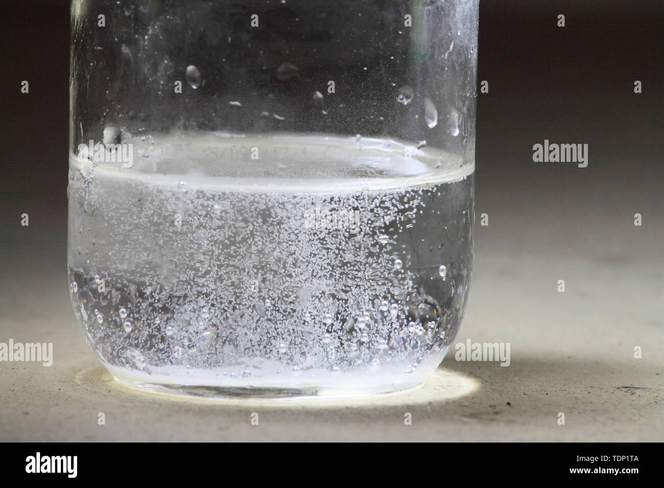 Primo piano di un aceto e bicarbonato di sodio la reazione avvenendo nel  fondo di un barattolo di vetro; la maggior parte di liquido chiaro con  bolle Foto stock - Alamy