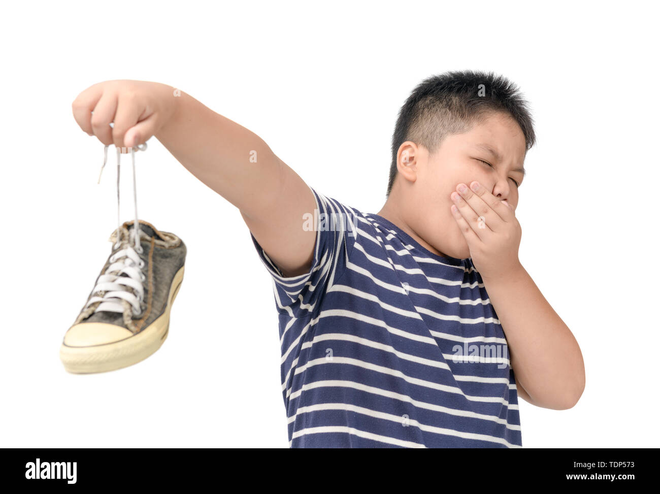 Disgustato fat boy tenendo un paio di puzzolente e stinky scarpe isolati su sfondo bianco, Foto Stock