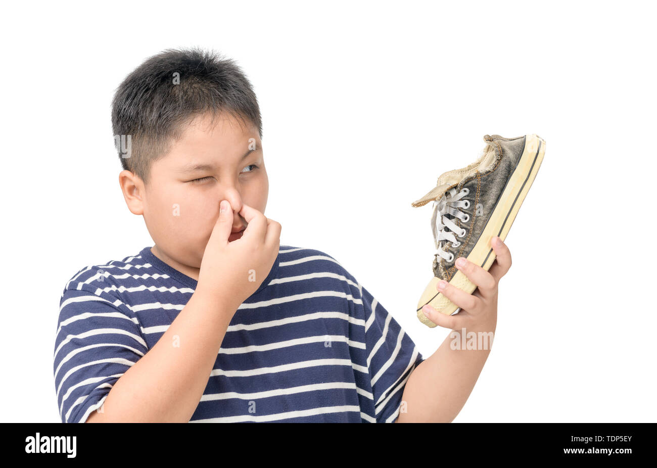 Disgustato fat boy tenendo un paio di puzzolente e stinky scarpe isolati su sfondo bianco, Foto Stock