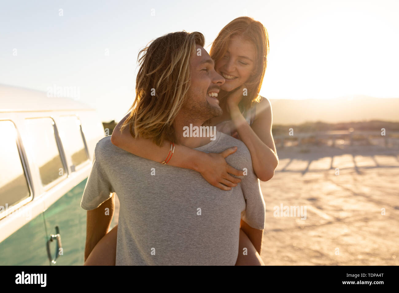 L uomo dando sovrapponibile alla donna vicino a camper van a beach Foto Stock