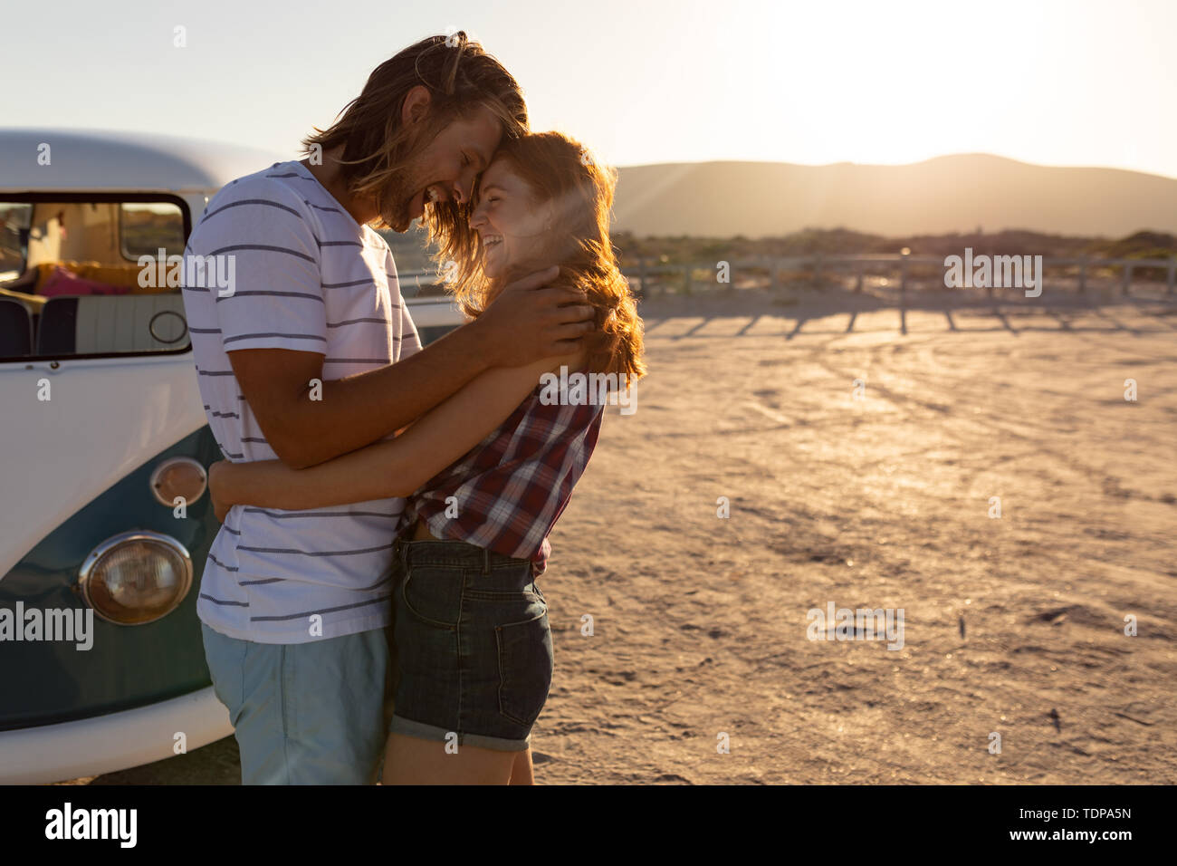 Felice coppia giovane che abbraccia ogni altra vicino camper presso la spiaggia Foto Stock