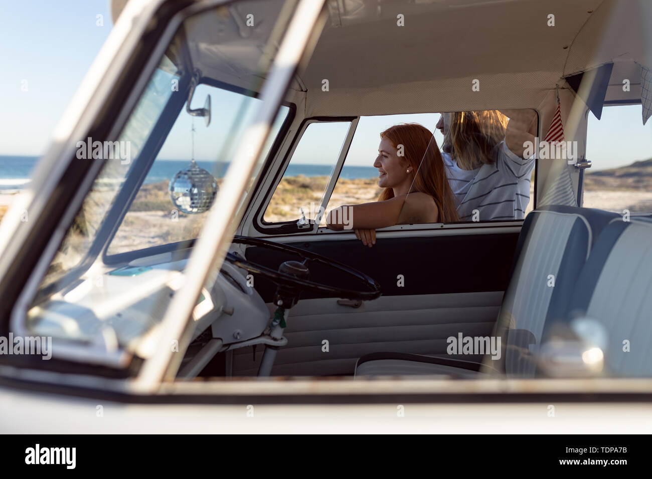 Felice coppia giovane che guarda lontano vicino a camper van a beach Foto Stock