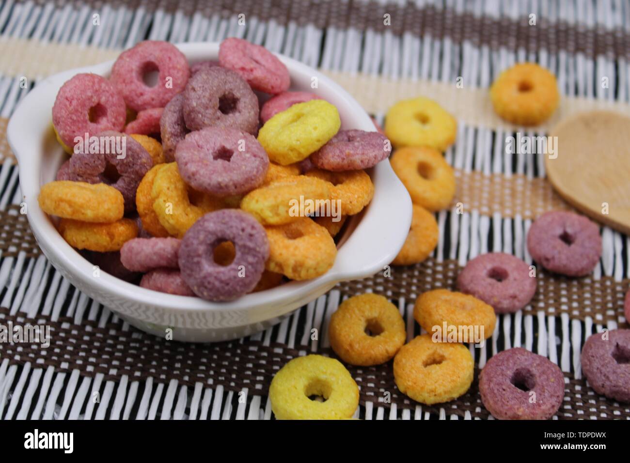 Di piccole dimensioni e di colore bianco con vaso colorato round cereali e cucchiaio di legno Foto Stock