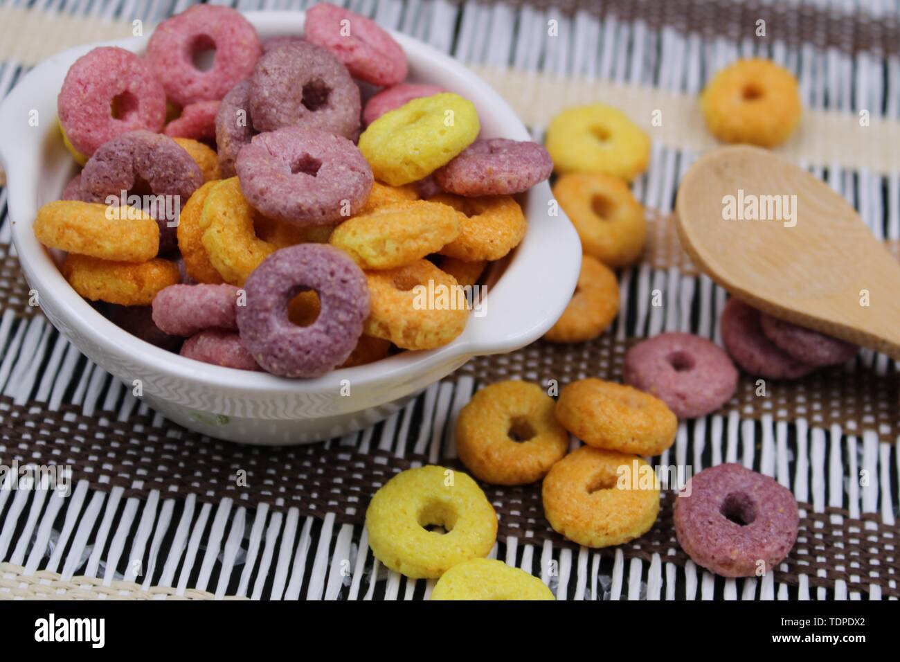 Di piccole dimensioni e di colore bianco con vaso colorato round cereali e cucchiaio di legno Foto Stock
