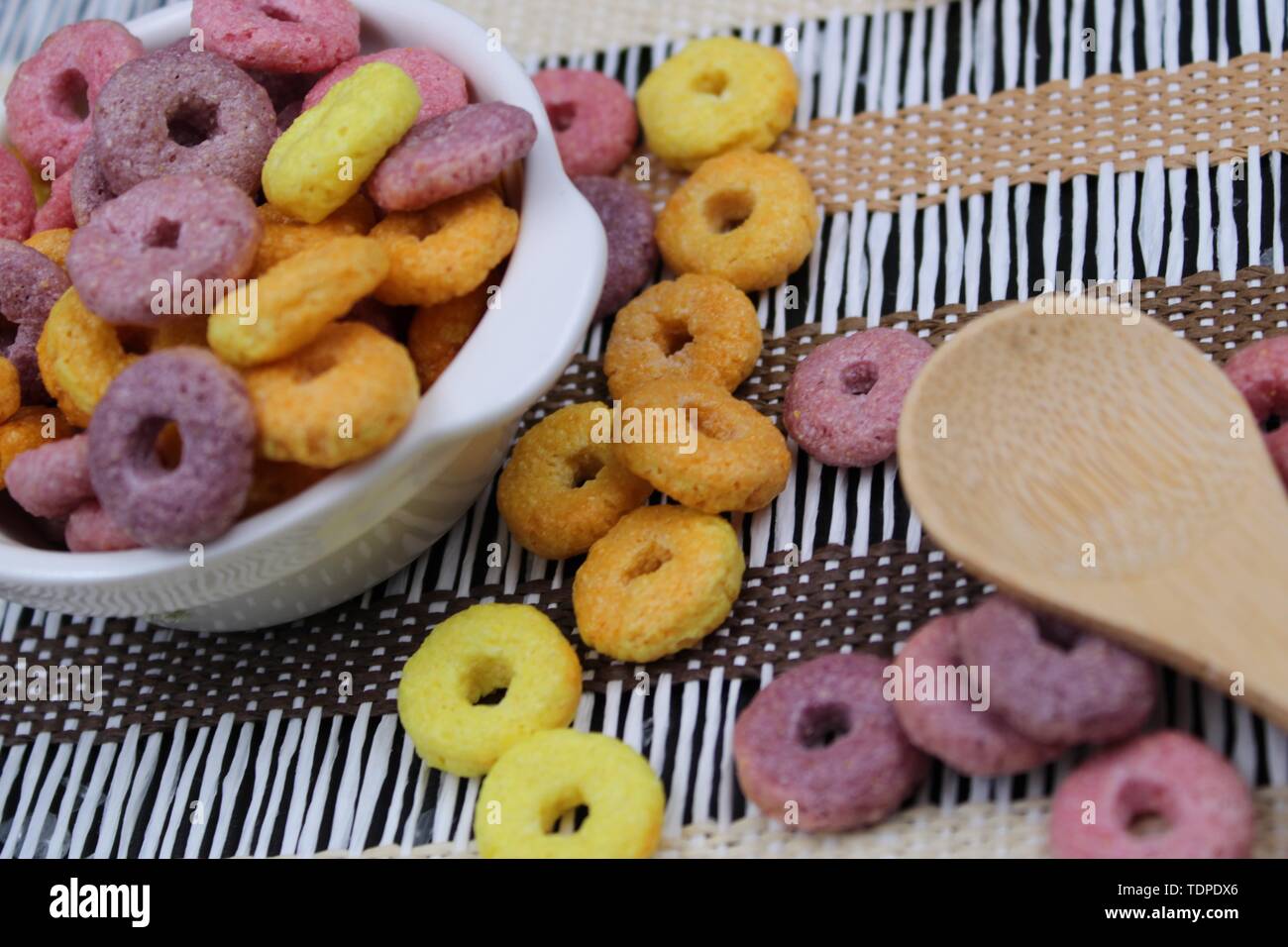 Di piccole dimensioni e di colore bianco con vaso colorato round cereali e cucchiaio di legno Foto Stock