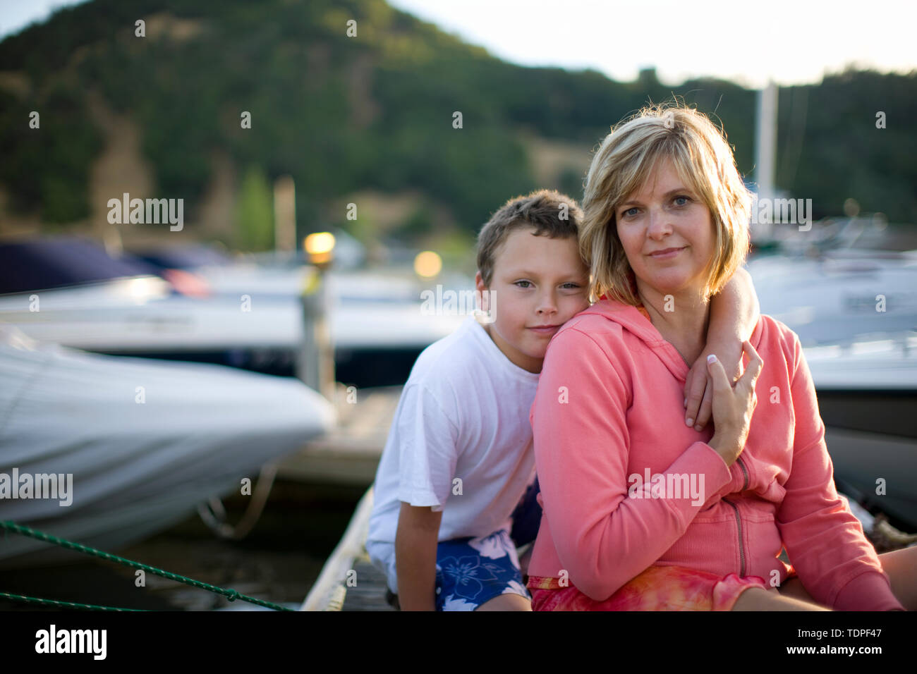 Ritratto di una madre e suo figlio seduto vicino a barche ormeggiate in banchina. Foto Stock