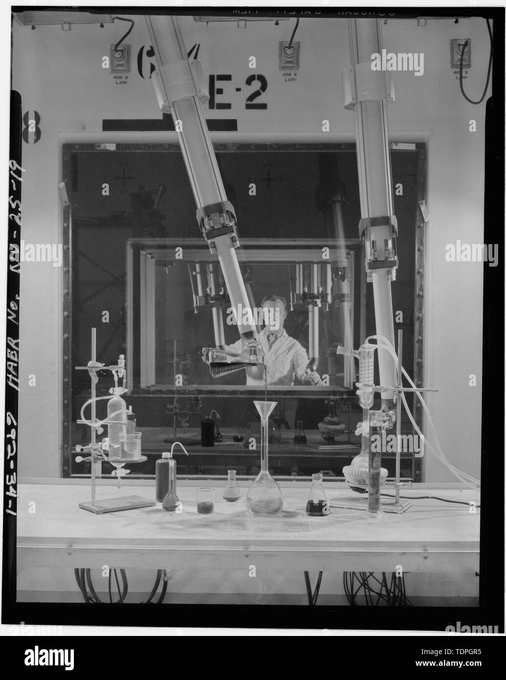 . Vista del lavoratore la manipolazione di piccoli oggetti in vetro nel caldo Bay con bracci manipolatori SULLA STAZIONE DI LAVORO E-2. Fotografo sconosciuto, ca. 1969, fotografia originale e negativo sul file presso il Laboratorio di Telerilevamento, Dipartimento di Energia, Nevada Ufficio Operazioni. - Nevada Test Site, manutenzione motore di assemblaggio e disassemblaggio Facility, Area 25, Jackass Flats, Mercurio, Nye County, NV Foto Stock