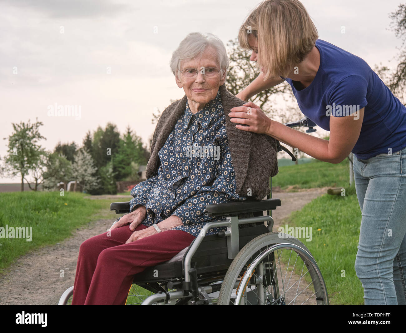 Il caregiver aiuta preoccupato senior lady in carrozzella Foto Stock