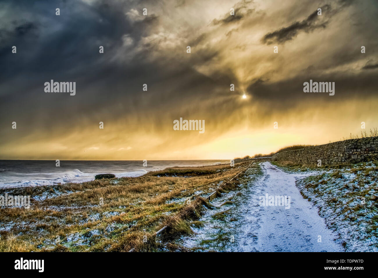 Coperte di neve il percorso lungo la costa dorata con la luce del sole illuminando le nubi; South Shields, Tyne and Wear, Inghilterra Foto Stock
