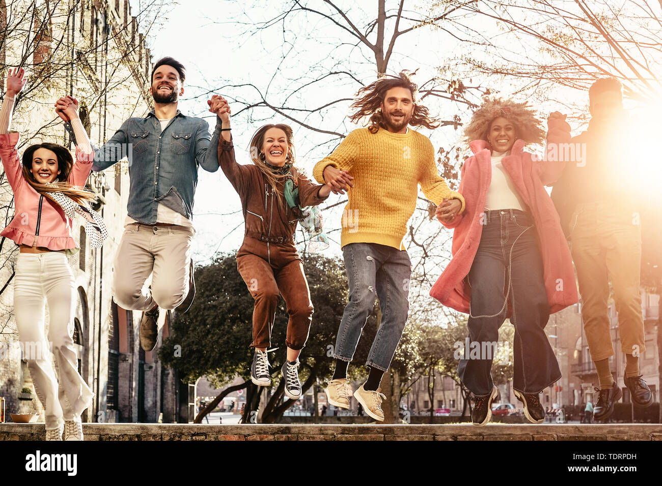 Gruppo di amici felice jumping outdoor - la millenaria giovani divertirsi ballare e festeggiare al tramonto al di fuori Foto Stock