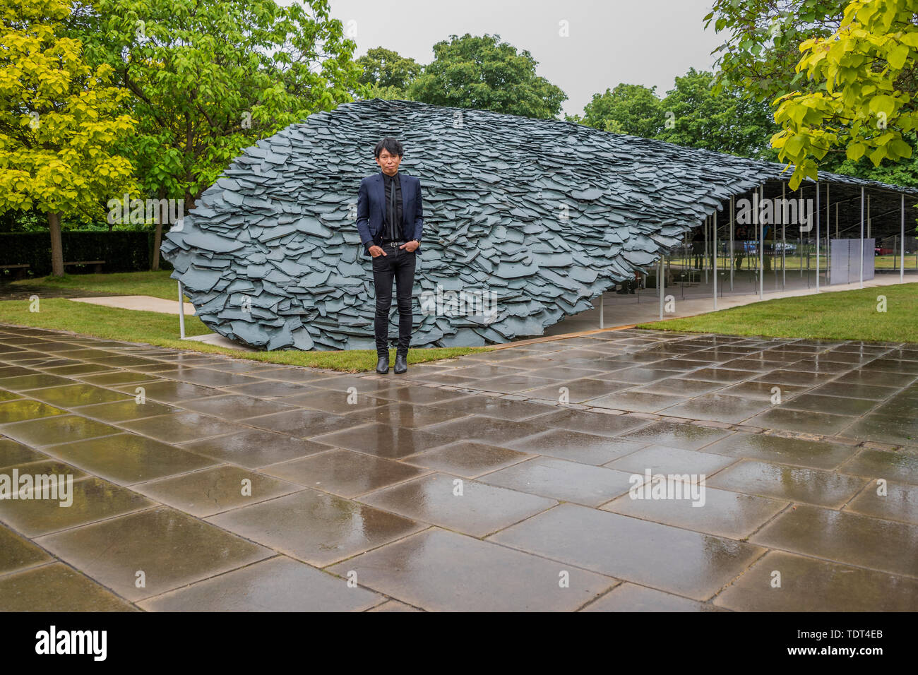 Londra, Regno Unito. Il 18 giugno, 2019. Serpentine Pavilion 2019, progettato dall architetto giapponese Junya Ishigami (nella foto). Il suo design prende ispirazione dai tetti e è realizzata disponendo le liste per creare un unico tettuccio che sembra emergere dal suolo del parco circostante. All'interno, la parte interna del padiglione è una grotta chiusa-come lo spazio, un rifugio per la contemplazione. Esso si articola il suo "spazio libero" filosofia nella quale egli cerca di armonia tra strutture artificiali e quelli che già esistono in natura. Aperto al pubblico il 21 giugno - 6 ottobre 2019. Credito: Guy Bell/Alamy Live News Foto Stock