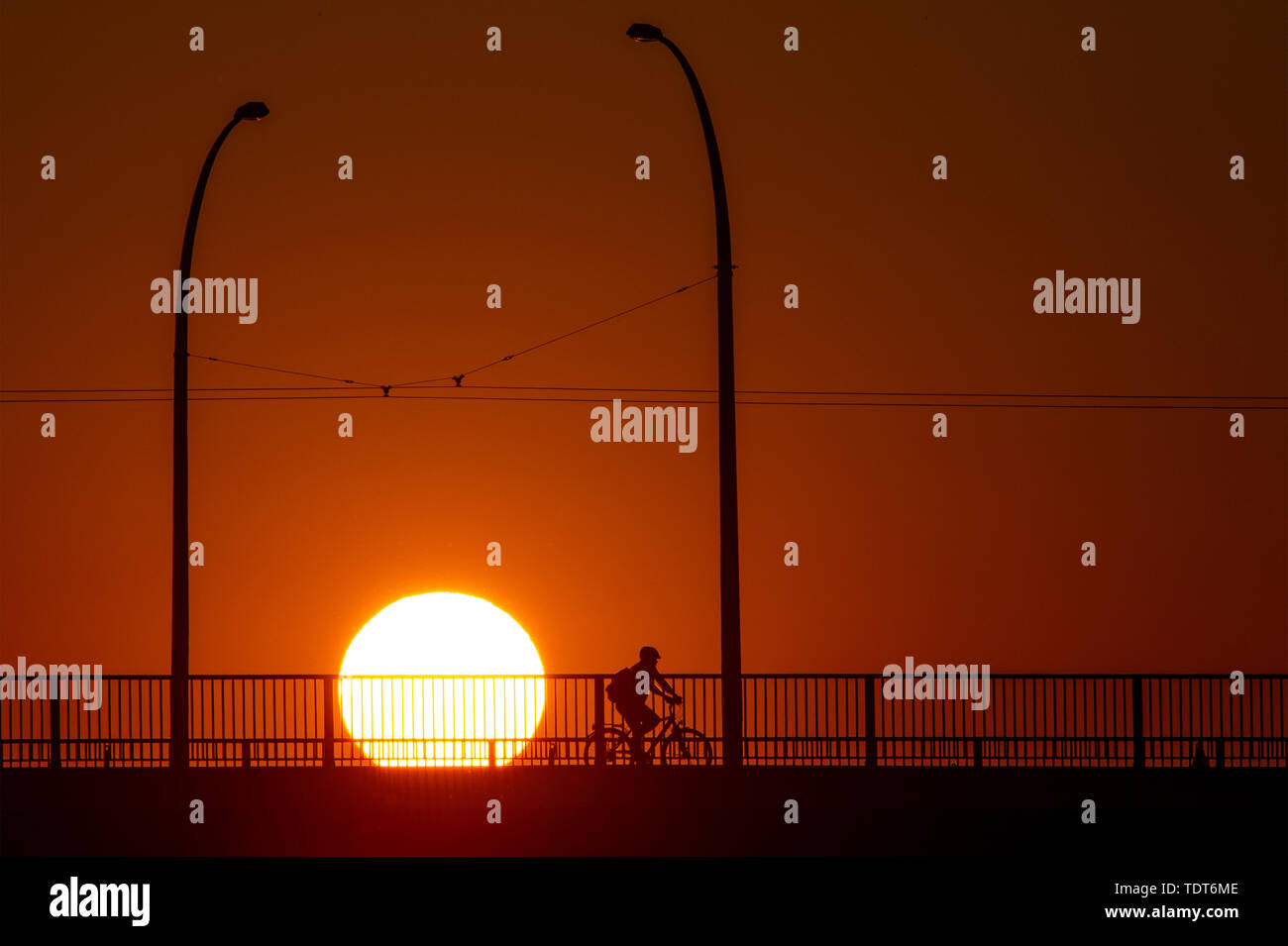 Magdeburg, Germania. Il 18 giugno, 2019. Un ciclista attraversa un ponte a sunrise. La regione intorno alla capitale dello stato è rivolta verso una calda e soleggiata giornata estiva. È sempre caldo. Nel tardo pomeriggio la temperatura deve essere al di sopra dei 30 gradi Celsius. Credito: Klaus-Dietmar Gabbert/dpa-Zentralbild/ZB/dpa/Alamy Live News Foto Stock