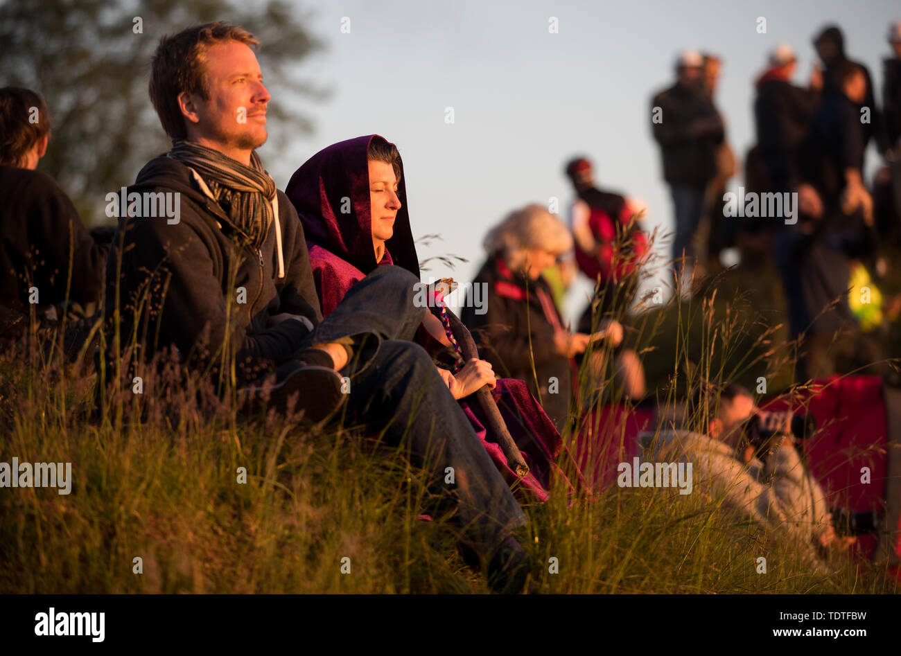 Persone si bagnano in presenza di luce solare come guardare il sole sorgere all'Avebury Stone Circle nel Wiltshire, dove si sono riuniti per celebrare l'alba del giorno più lungo nel Regno Unito. Foto Stock