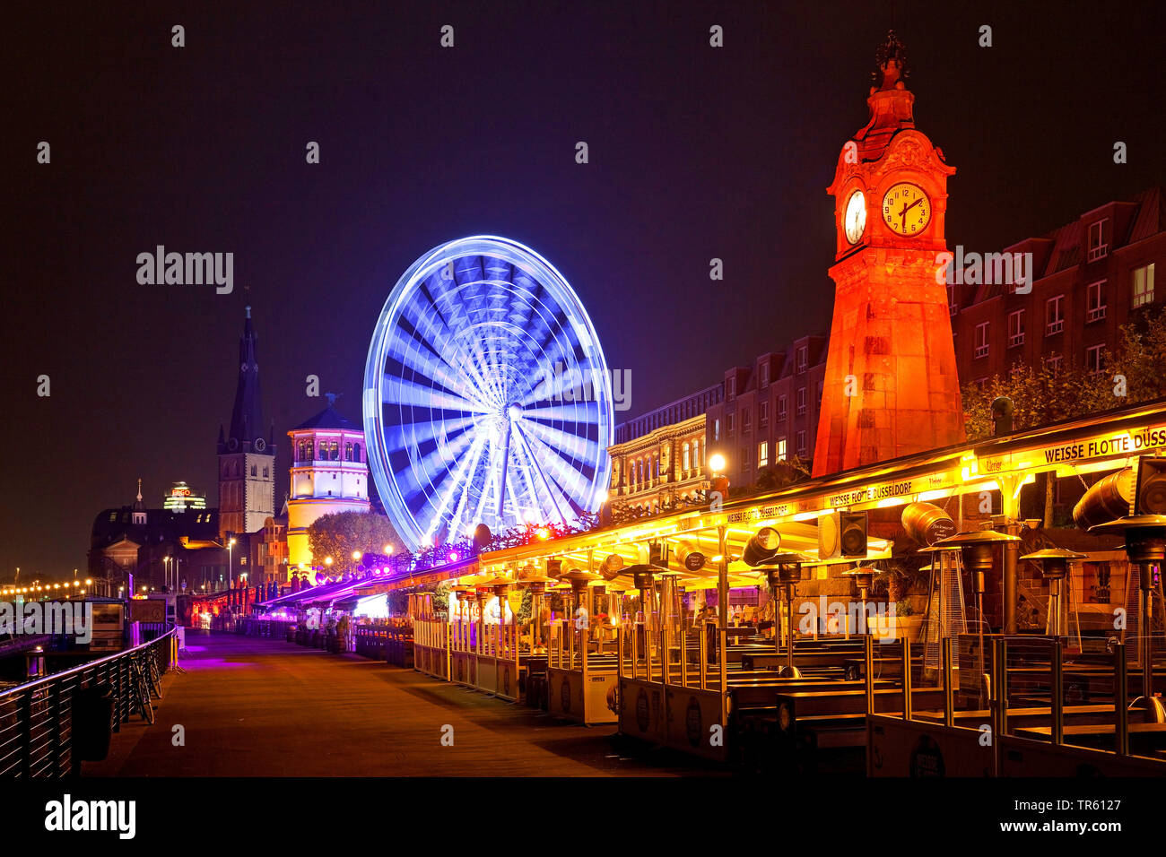 La passeggiata sul lungofiume del Reno con illuminato marcatore di inondazioni e la ruota panoramica Ferris di sera , in Germania, in Renania settentrionale-Vestfalia, Duesseldorf Foto Stock