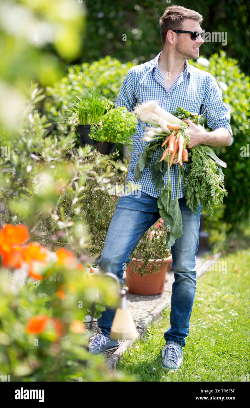 Uomo di fresco con verdure raccolte in piedi nel giardino, Germania Foto Stock