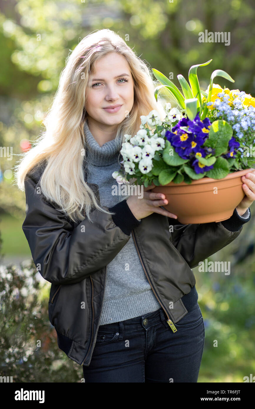 Giovane donna bionda con un vaso di fiori, Germania Foto Stock