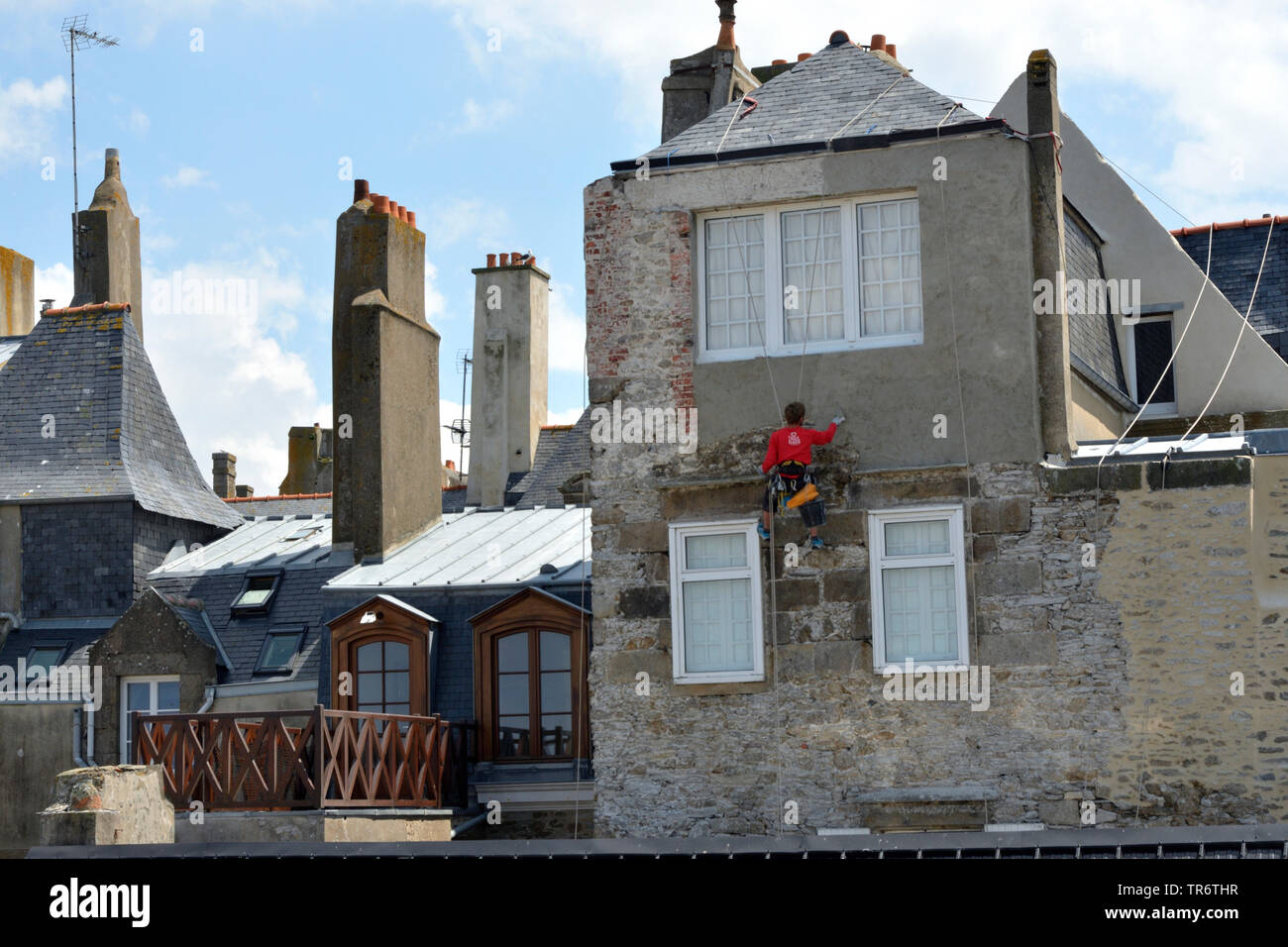 Muratore rappeling da un tetto ed intonaci di facciata nella città vecchia, Francia Bretagna, Saint-Malo Foto Stock