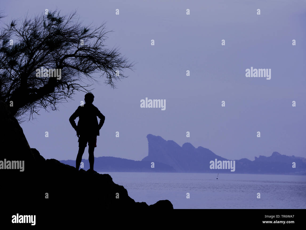 Silhouette di un vagabondo guardando il mare costa rocciosa dei Calanchi con Bec de l'Aigle in background, Francia Provenza Foto Stock
