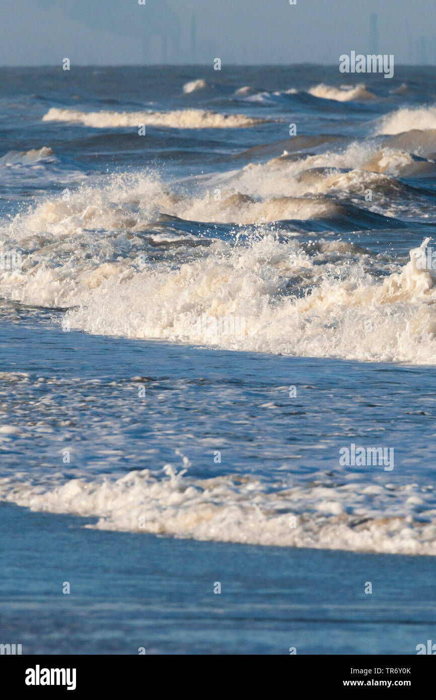 Le onde del mare del Nord in inverno con comignoli fumanti in background, Paesi Bassi, South Holland, Katwijk aan Zee Foto Stock