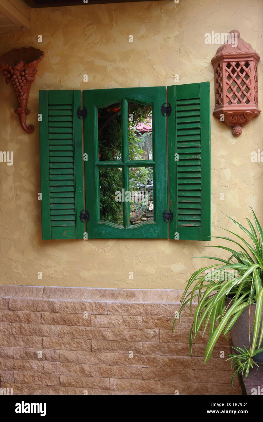Finestra decorativo con persiane di legno verde sulla parete di una casa di  campagna Foto stock - Alamy